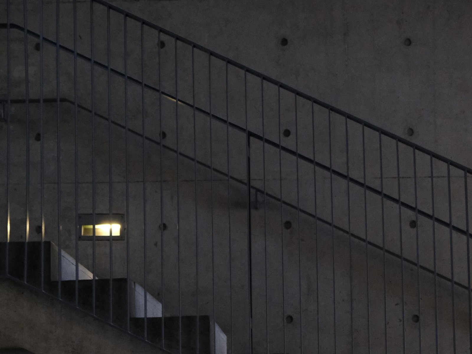 Duotone detail of a sculptural concrete stairwell at dusk